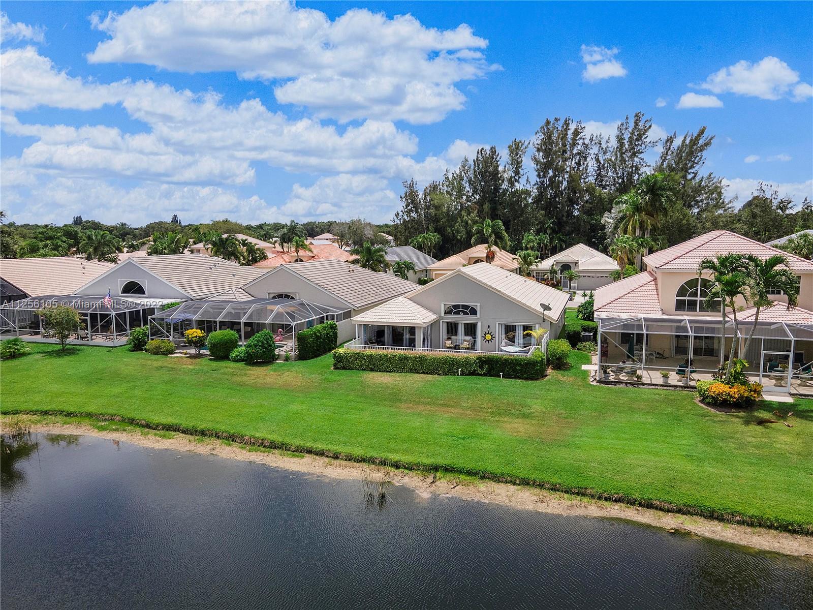 7677 Doubleton Drive Delray Beach, FL 33446 - Photo 6 of 42 a front view of a house with a garden and trees