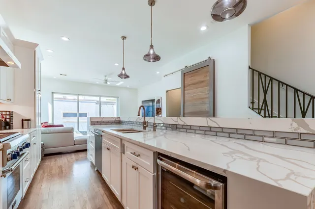 a kitchen with stainless steel appliances granite countertop a sink a stove and a wooden floors