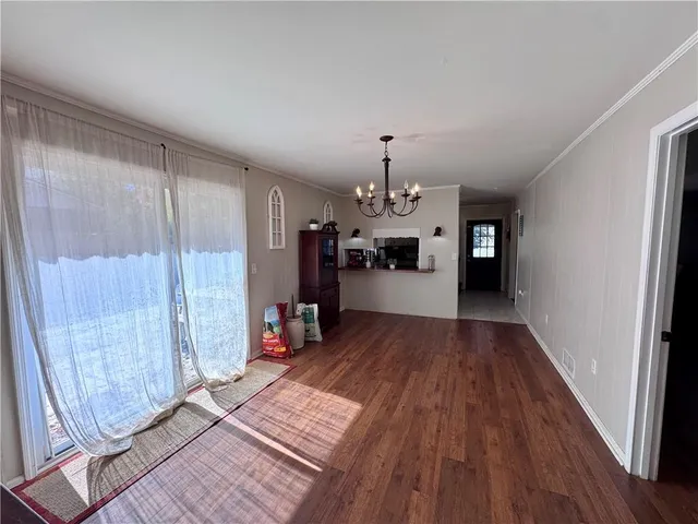 an empty room with wooden floor and a chandelier