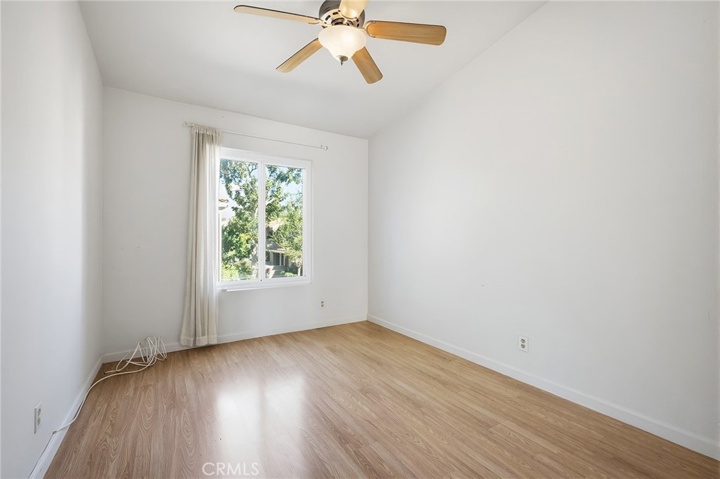 8167 Vineyard Avenue, Unit 47 Rancho Cucamonga, CA 91730 - Photo 17 of 22 an empty room with wooden floor chandelier fan and windows