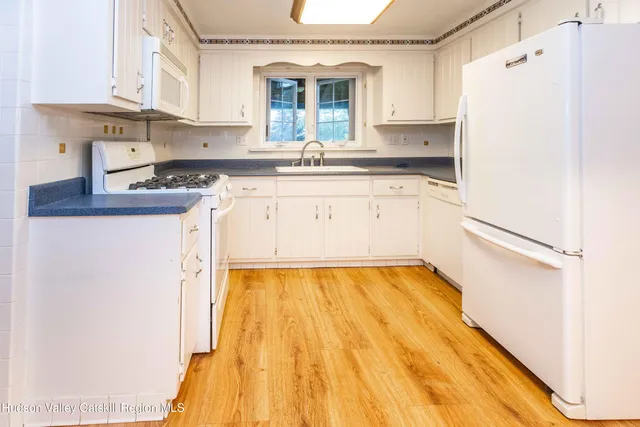 a kitchen with a sink a refrigerator and white cabinets