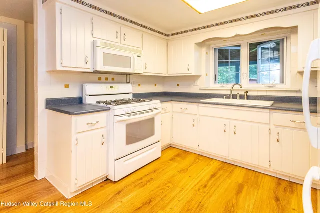 a kitchen with granite countertop white cabinets and white appliances
