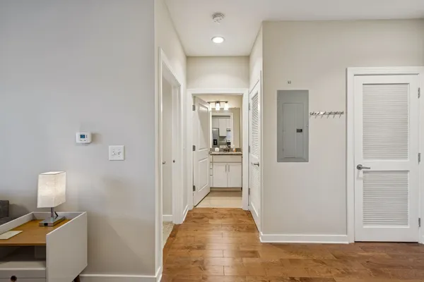 a view of a hallway with wooden floor and a bathroom