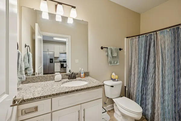 a bathroom with a granite countertop toilet a sink and a mirror