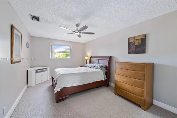 a spacious bedroom with a bed a dresser and painting on the wall