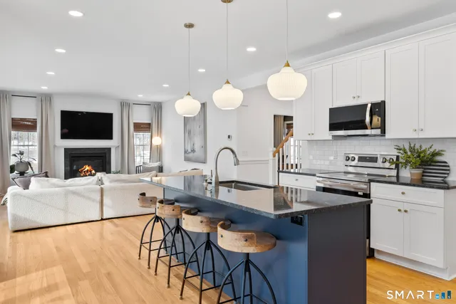 a kitchen with stainless steel appliances granite countertop a stove top oven a sink dishwasher a dining table and chairs with wooden floor