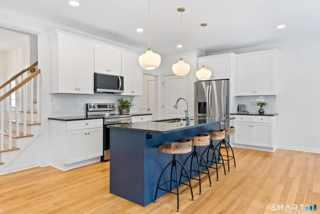 a kitchen with stainless steel appliances granite countertop a sink a stove a refrigerator and a microwave