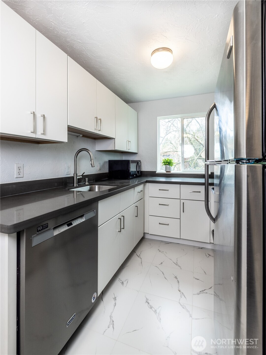 2100 North 106th Street, Unit 307 Seattle, WA 98133 - Photo 3 of 11 a kitchen with a sink cabinets appliances and windows