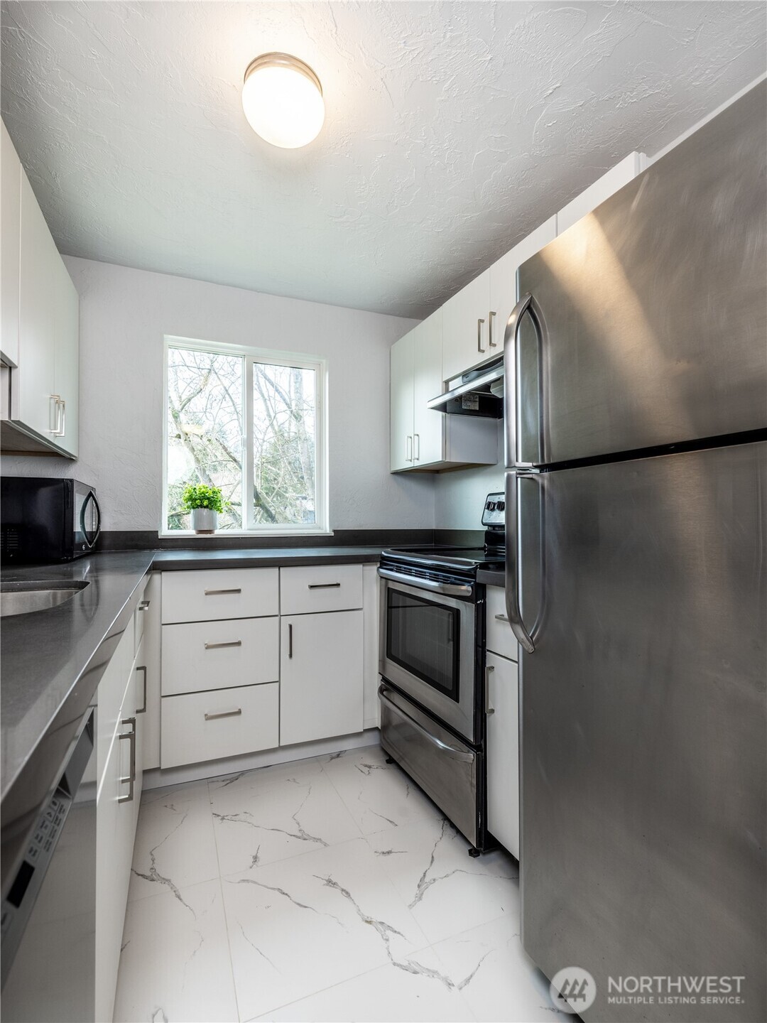 2100 North 106th Street, Unit 307 Seattle, WA 98133 - Photo 4 of 11 a kitchen with cabinets stainless steel appliances and window