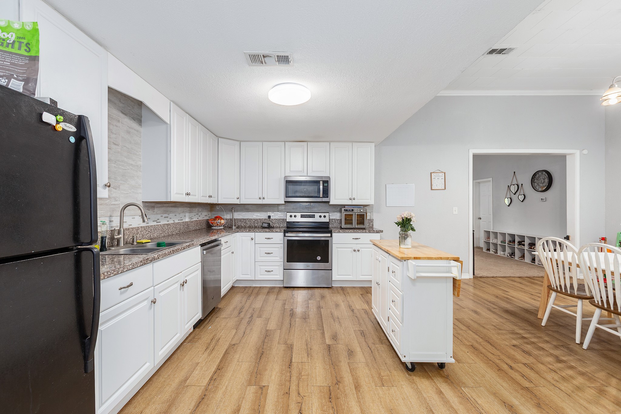 240 North 7th Street Trinity, TX 75862 - Photo 21 of 32 a kitchen with granite countertop a refrigerator a stove top oven a dining table and chairs with wooden floor