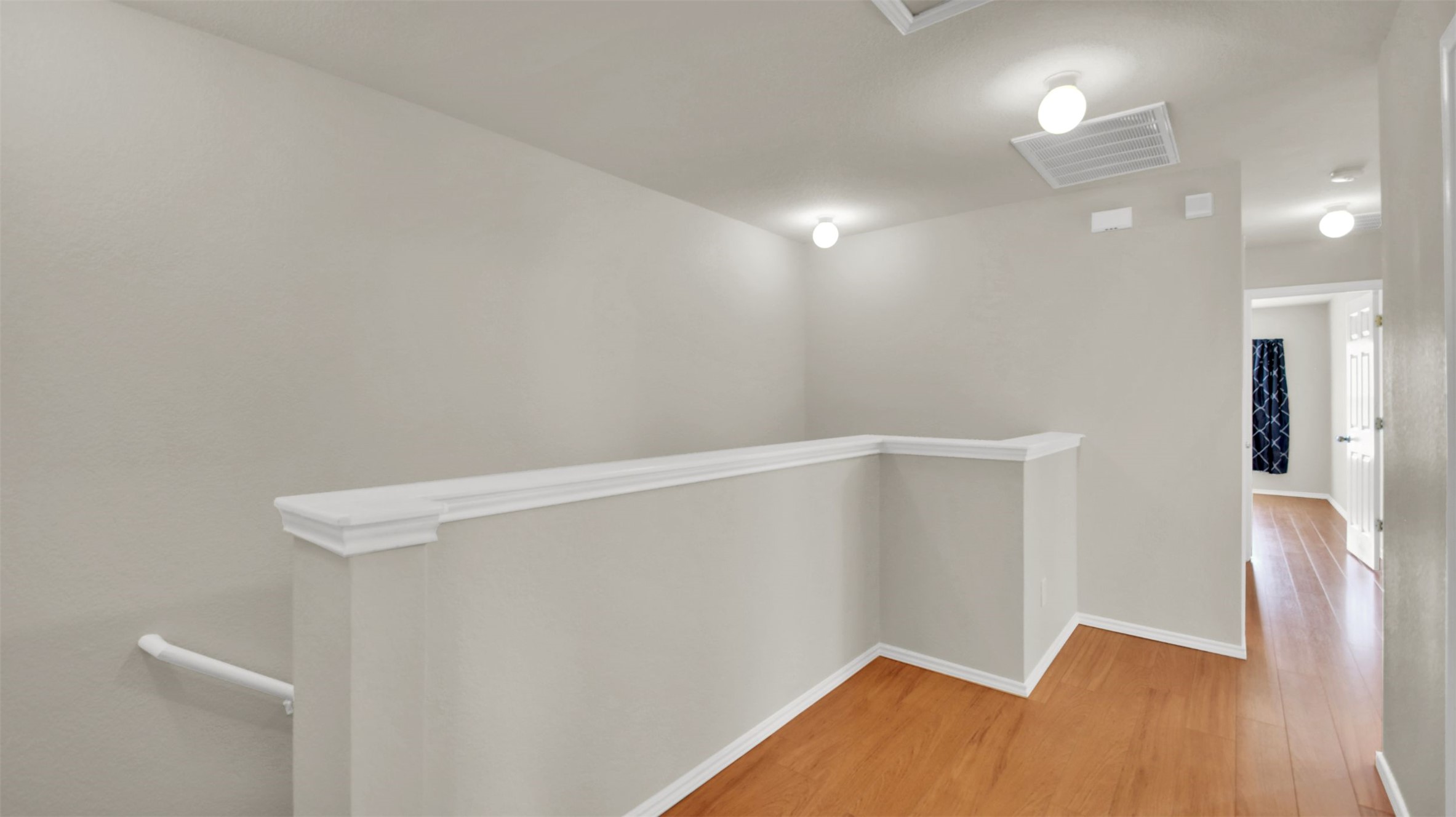 73 Verde Ranch Loop Leander, TX 78641 - Photo 24 of 29 Corridor with visible vents, wood finished floors, and an upstairs landing