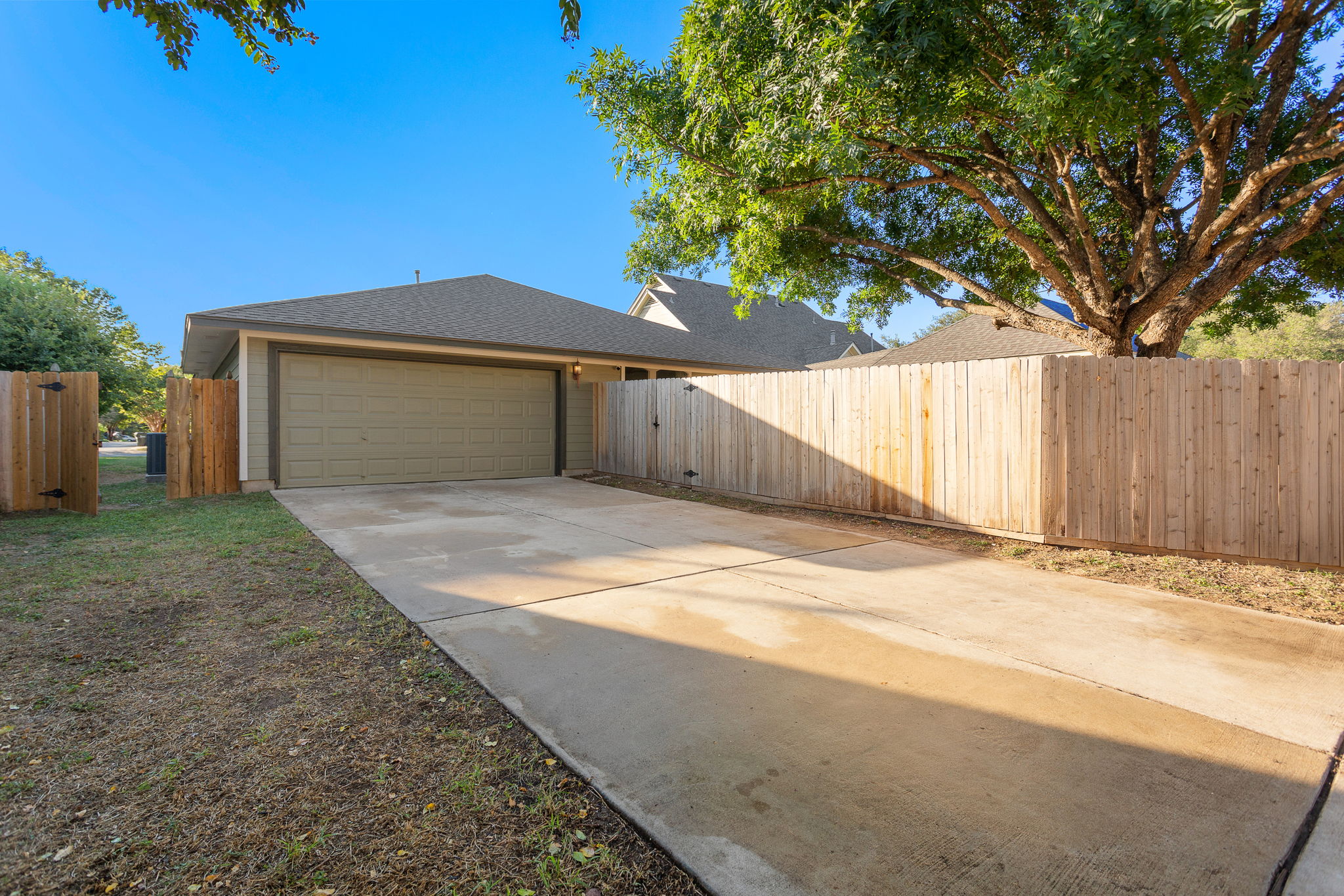 313 Greenside Lane Georgetown, TX 78633 - Photo 11 of 40 View of side of home featuring concrete driveway, an attached garage, a shingled roof, and a gate