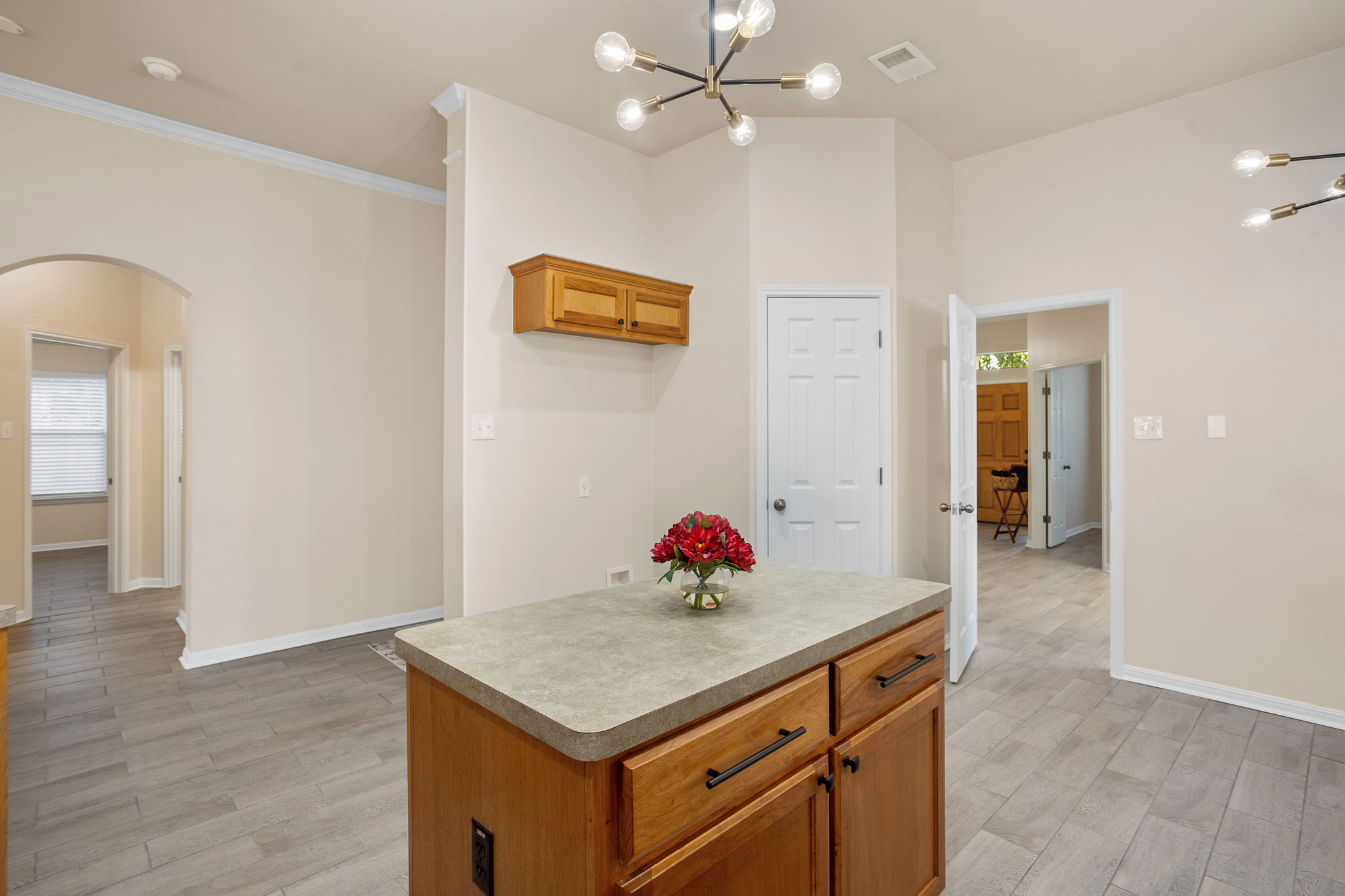 313 Greenside Lane Georgetown, TX 78633 - Photo 13 of 40 Kitchen featuring wood finish cabinets, arched walkways, suspended lighting, light wood-style floors, and a center island
