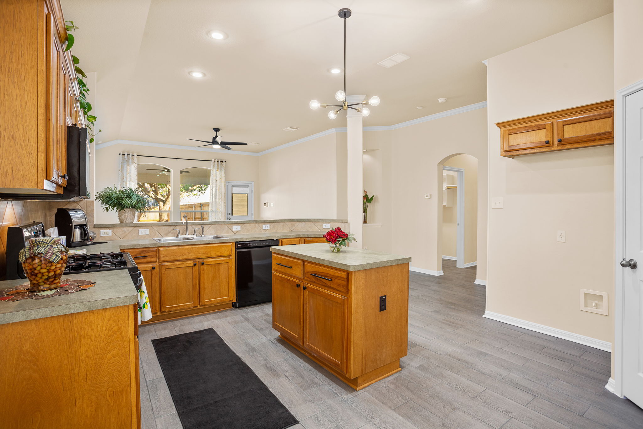 313 Greenside Lane Georgetown, TX 78633 - Photo 16 of 40 Kitchen featuring wood finish cabinets, arched walkways, light countertops, backsplash, and ornamental molding