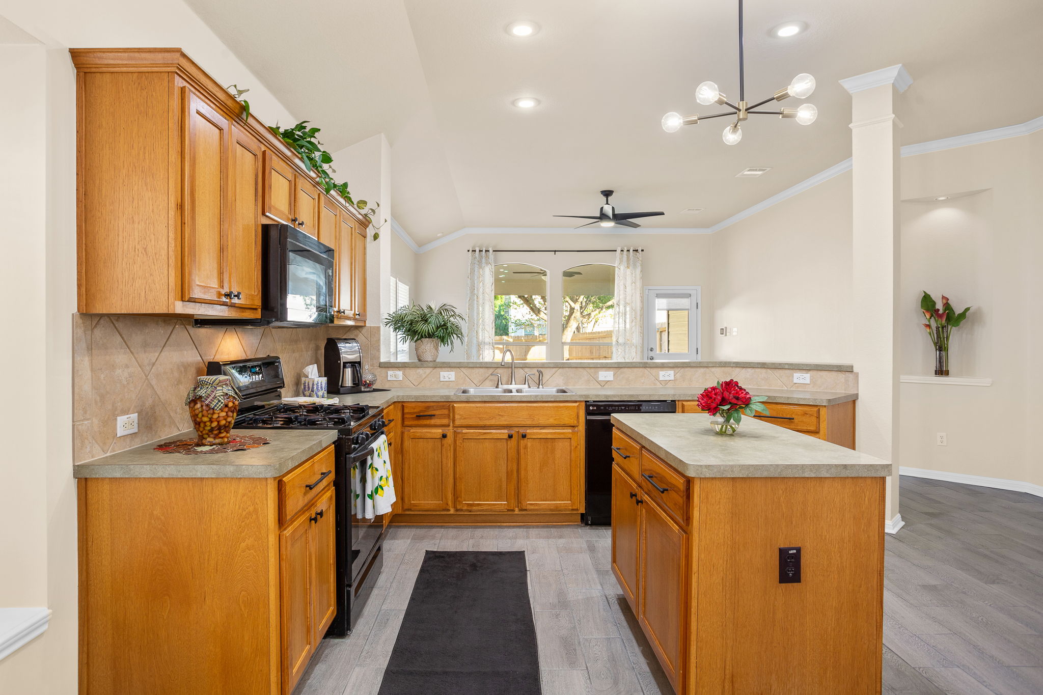 313 Greenside Lane Georgetown, TX 78633 - Photo 17 of 40 Kitchen with black appliances, light countertops, decorative backsplash, a ceiling fan, and wood finish cabinetry