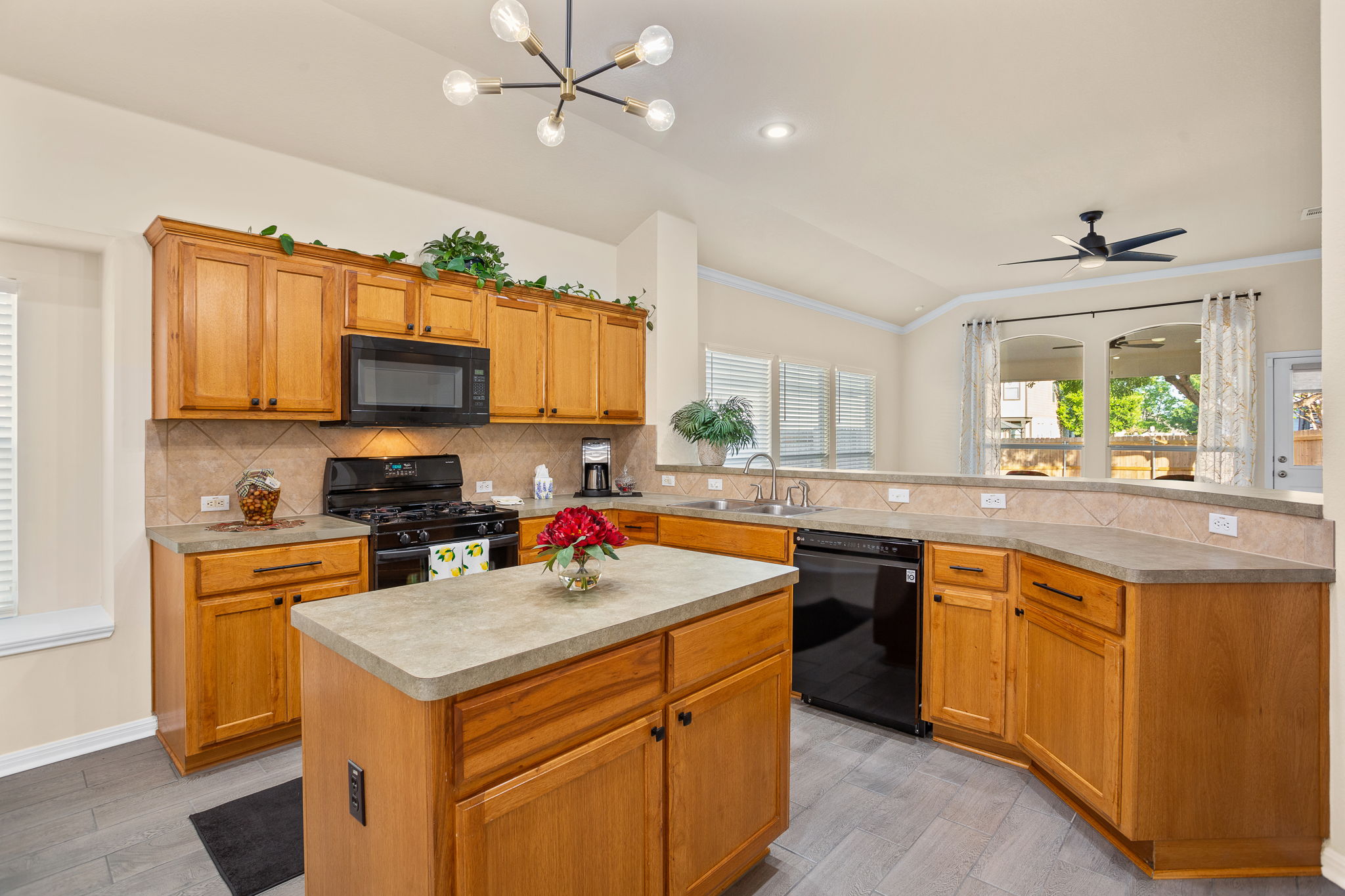 313 Greenside Lane Georgetown, TX 78633 - Photo 18 of 40 Kitchen with black appliances, a peninsula, a center island, light countertops, and tasteful backsplash