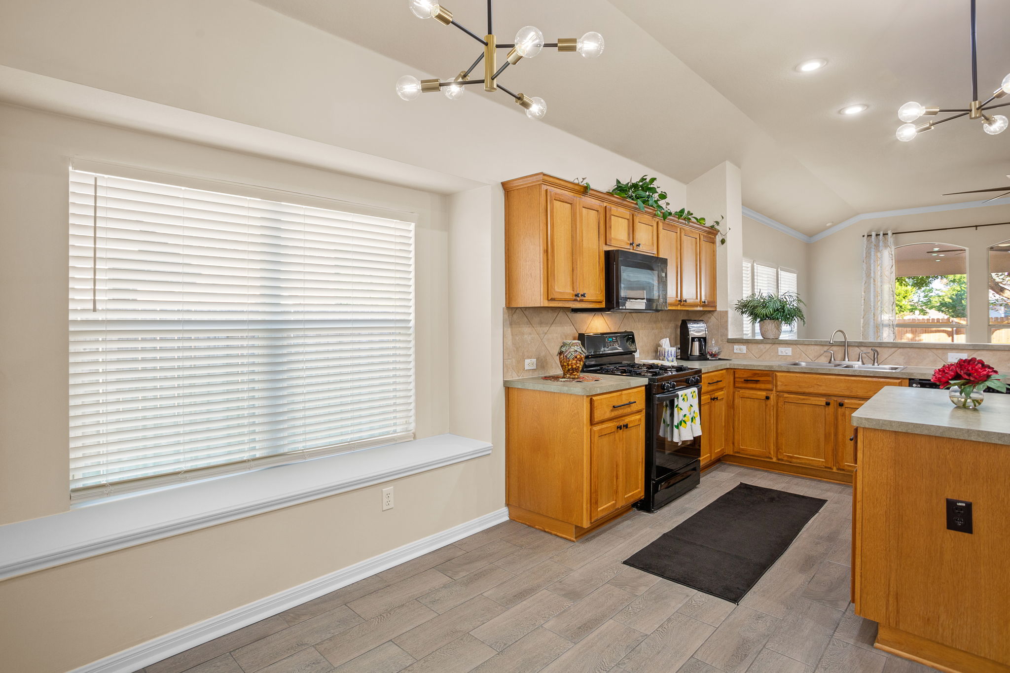 313 Greenside Lane Georgetown, TX 78633 - Photo 19 of 40 Kitchen with a chandelier, black appliances, light countertops, light wood finished floors, and lofted ceiling