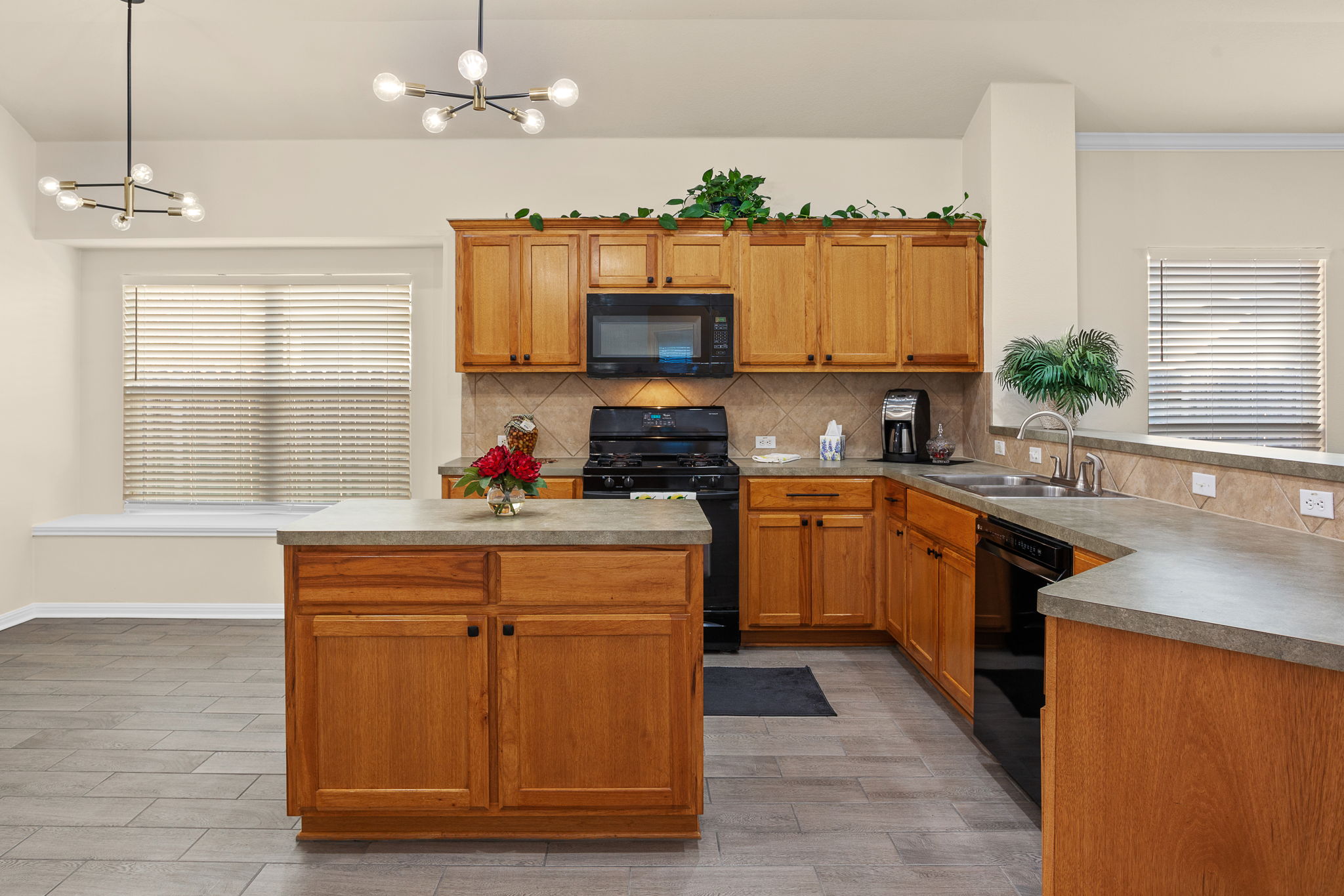 313 Greenside Lane Georgetown, TX 78633 - Photo 22 of 40 Kitchen with black appliances, light wood finished floors, wood finish cabinets, and a chandelier
