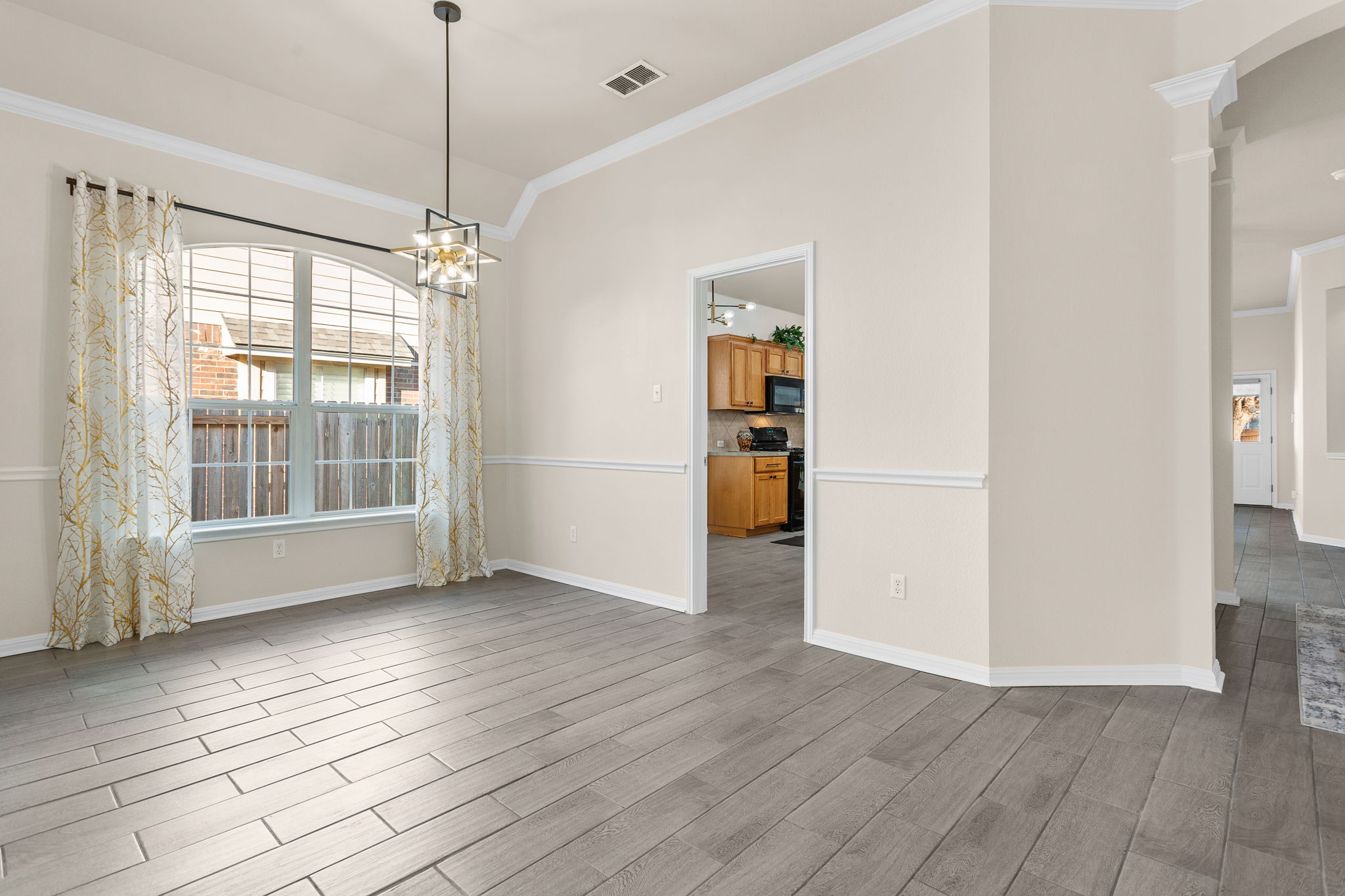 313 Greenside Lane Georgetown, TX 78633 - Photo 26 of 40 Unfurnished dining area featuring crown molding, light wood-style flooring, hanging lights, and arched walkways