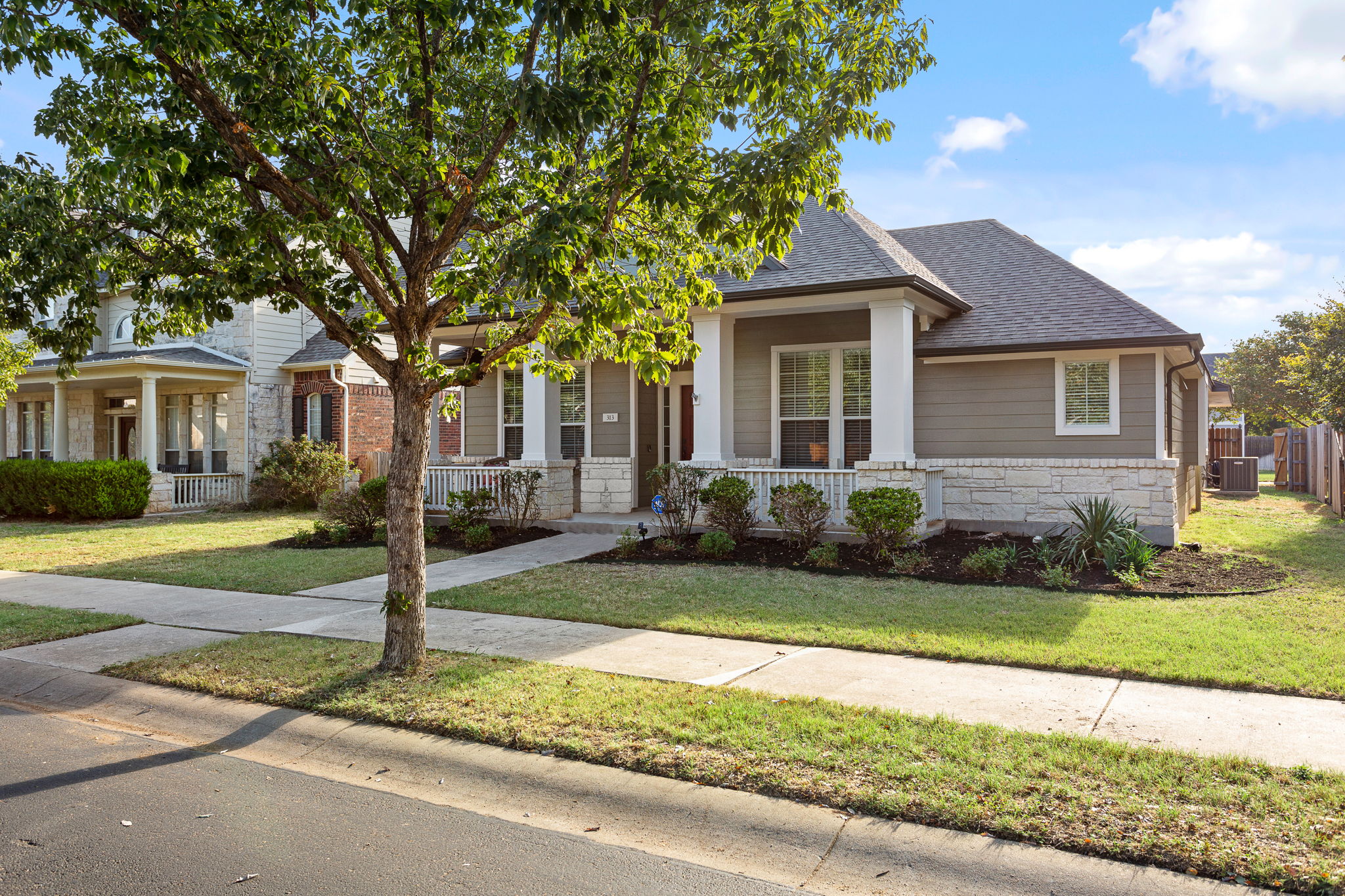 313 Greenside Lane Georgetown, TX 78633 - Photo 3 of 40 View of front of property featuring stone siding, covered porch, a shingled roof, and a front lawn