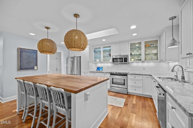 a kitchen with stainless steel appliances granite countertop a stove a sink a oven a dining table and chairs