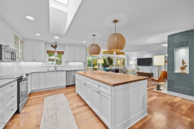 a kitchen with stainless steel appliances a stove a refrigerator a kitchen island and chairs in it