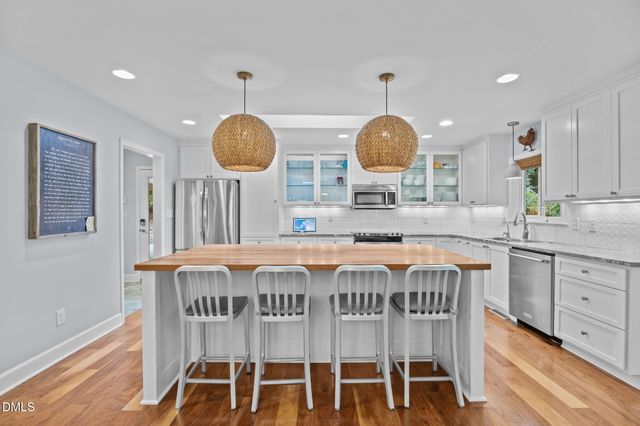a kitchen with stainless steel appliances granite countertop white cabinets and a stove top oven