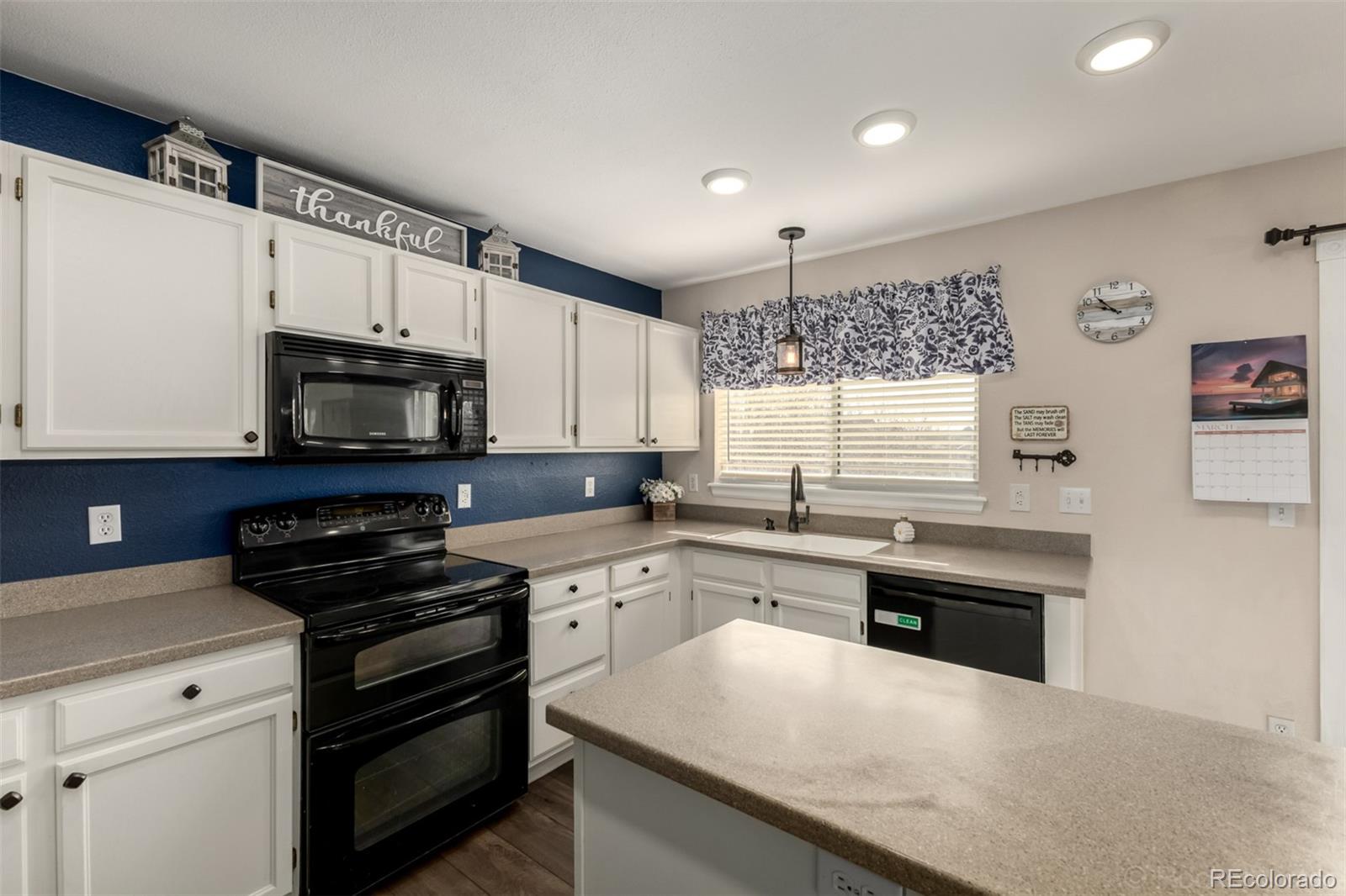 8894 Miners Street Highlands Ranch, CO 80126 - Photo 13 of 41 a kitchen with stainless steel appliances a stove sink microwave and cabinets