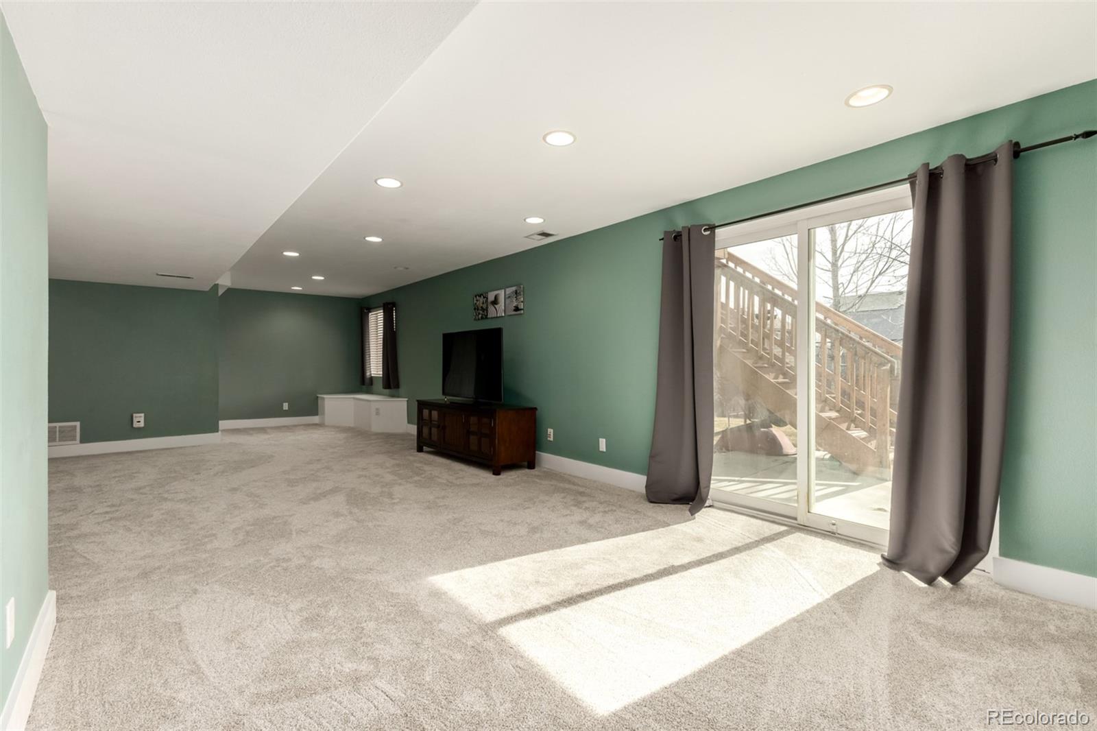 8894 Miners Street Highlands Ranch, CO 80126 - Photo 31 of 41 a large bedroom with a large bed and a flat tv screen next to a large window