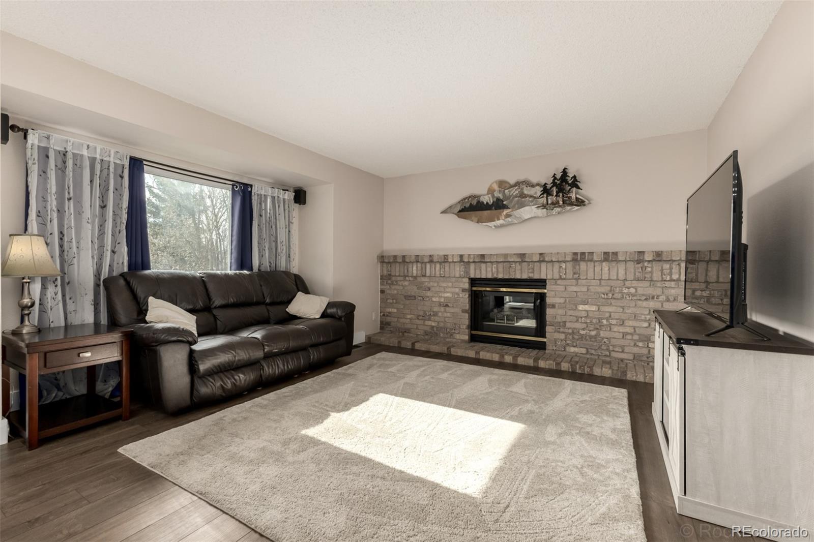 8894 Miners Street Highlands Ranch, CO 80126 - Photo 7 of 41 a living room with furniture a flat screen tv and a fireplace
