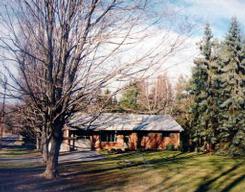 a front view of a house with a yard and large trees