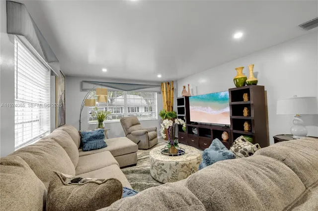 a living room with furniture kitchen view and a large window