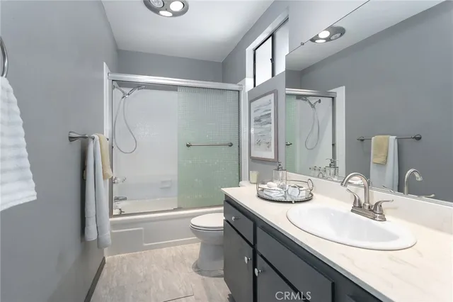 a bathroom with a granite countertop sink a toilet a mirror and shower