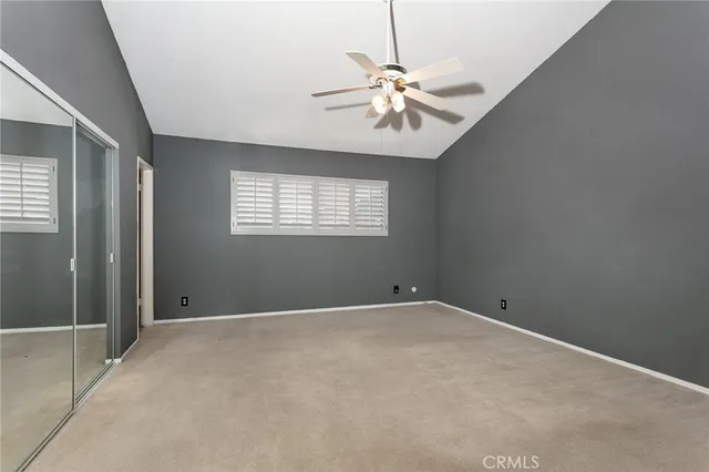 an empty room with windows and chandelier fan