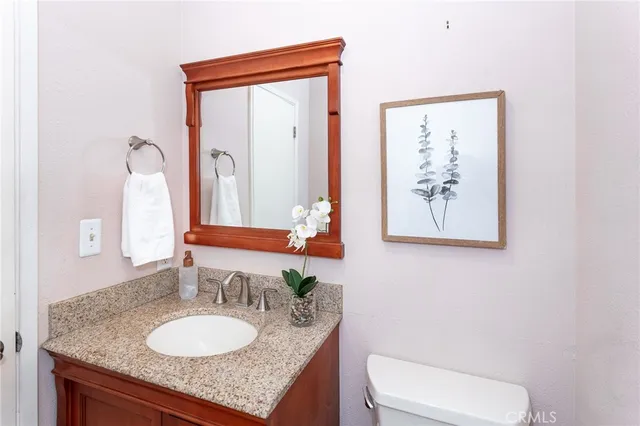 a bathroom with a granite countertop sink and a mirror with toilet