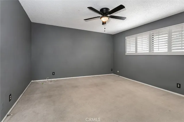 an empty room with a window and a fan