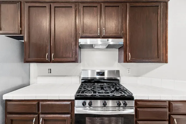 an empty room with wooden floor a ceiling fan and windows