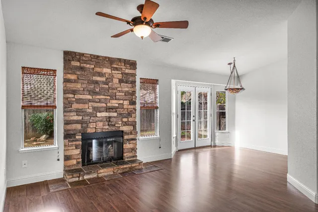 a view of an empty room with wooden floor and a ceiling fan