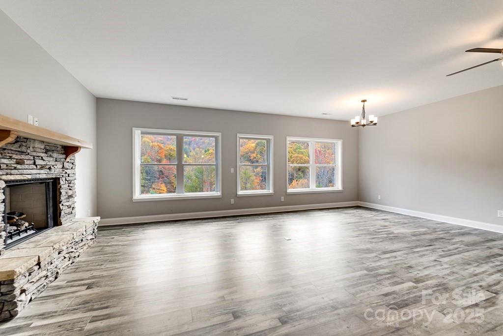 679 Firefly Road Whittier, NC 28789 - Photo 11 of 34 wooden floor fireplace and windows in an empty room