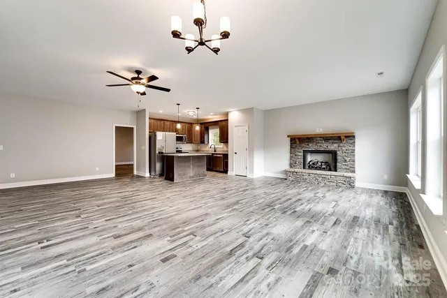 a view of a livingroom with a fireplace a ceiling fan and wooden floor
