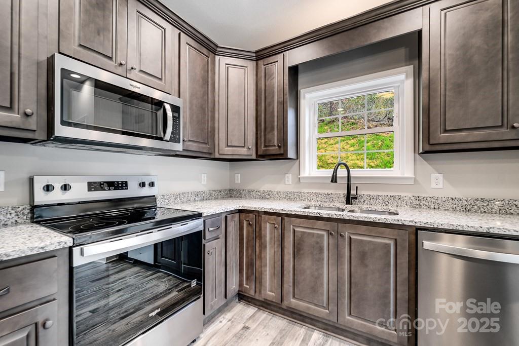 679 Firefly Road Whittier, NC 28789 - Photo 16 of 34 a kitchen with stainless steel appliances granite countertop a stove microwave and sink