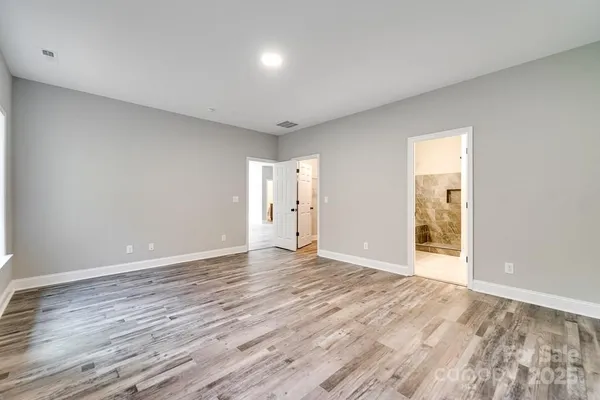 a view of an empty room with wooden floor and windows