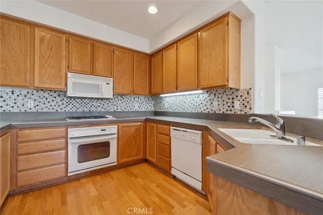 a kitchen with granite countertop wooden cabinets a sink and dishwasher a stove with wooden floor