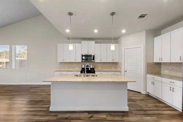 a large white kitchen with kitchen island a sink a center island stainless steel appliances and a counter space