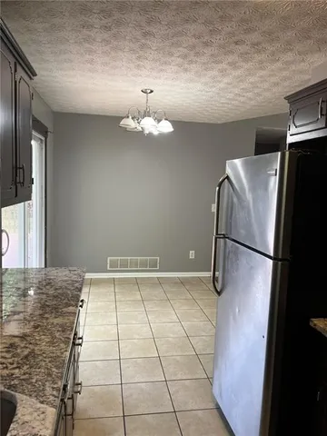 a view of a refrigerator in kitchen and an empty room