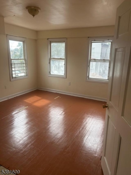 41 Myrtle Avenue Newark, NJ 07107 - Photo 7 of 10 an empty room with wooden floor and windows