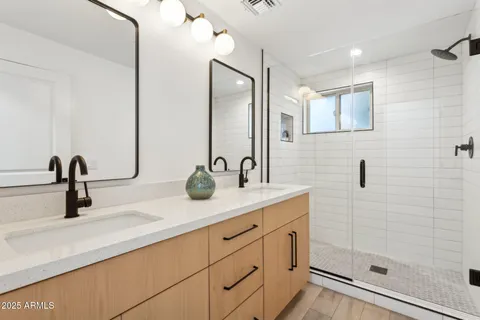 a bathroom with a double vanity sink mirror and shower