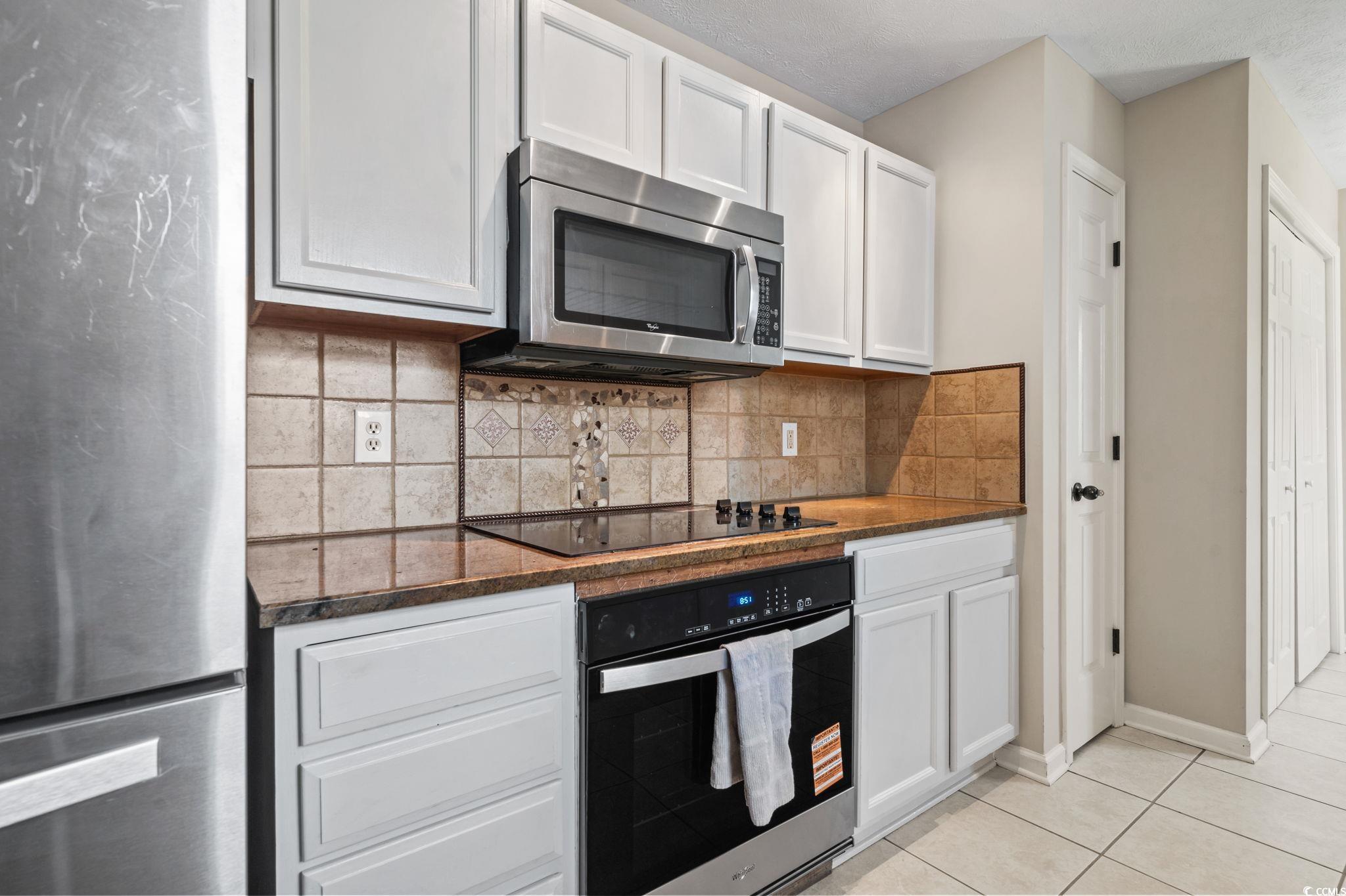 1007 Autumn Drive Murrells Inlet, SC 29576 - Photo 11 of 33 Kitchen with appliances with stainless steel finishes, white cabinets, light tile patterned floors, and backsplash