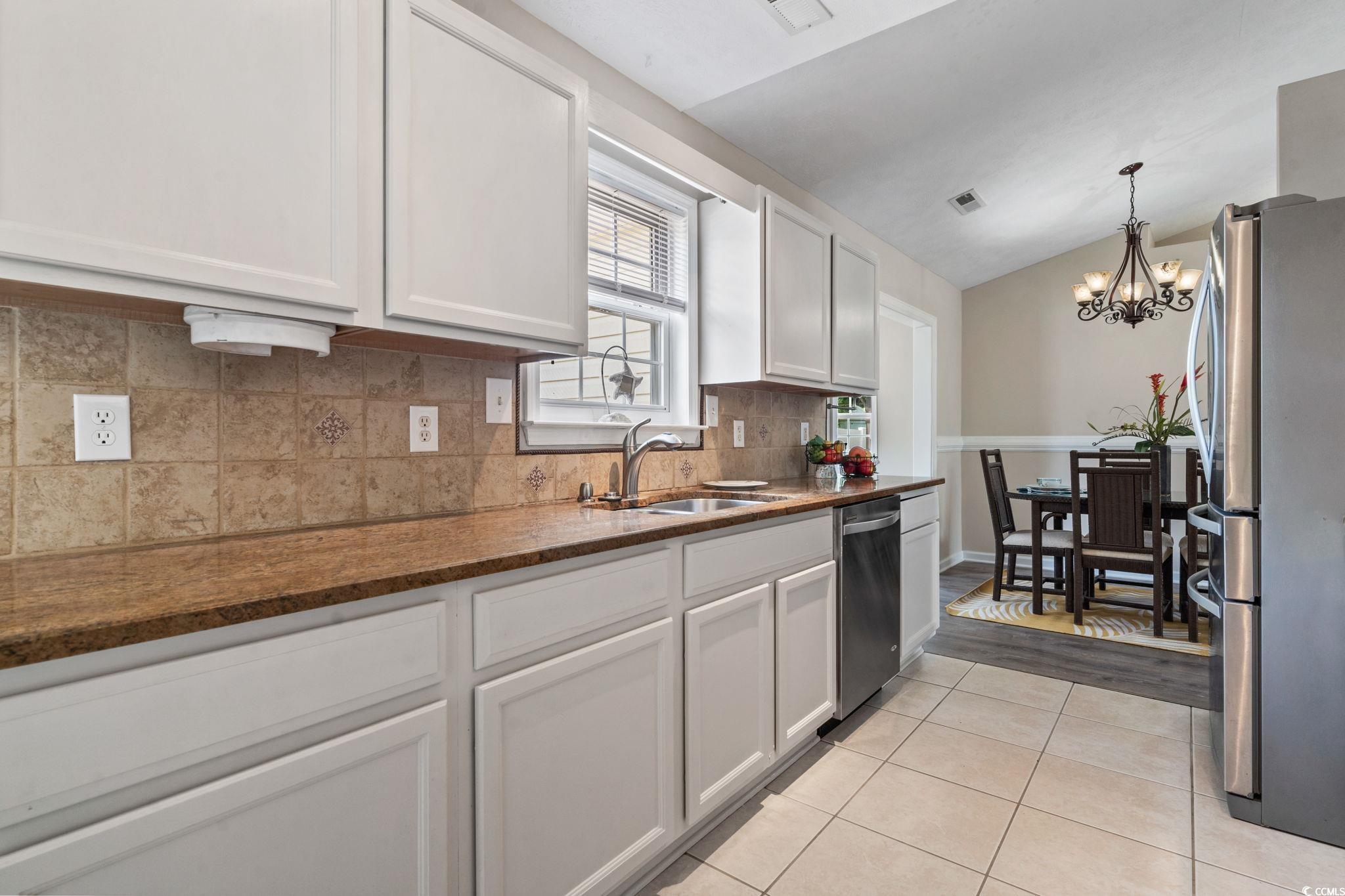 1007 Autumn Drive Murrells Inlet, SC 29576 - Photo 12 of 33 Kitchen with appliances with stainless steel finishes, light tile patterned flooring, a chandelier, white cabinetry, and tasteful backsplash