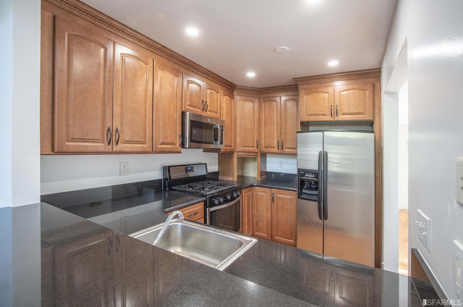 1253 Terra Nova Boulevard Pacifica, CA 94044 - Photo 6 of 23 a kitchen with stainless steel appliances granite countertop a refrigerator a stove and a sink with wooden floor